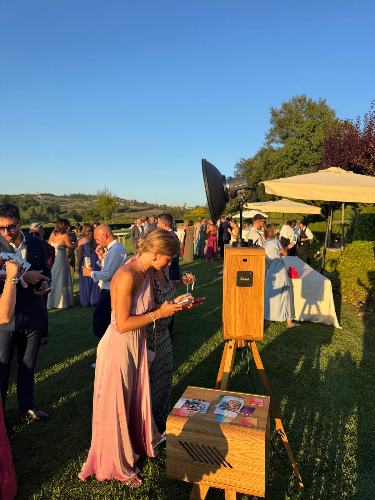 Ospite con smartphone accanto al photo booth durante un ricevimento all’aperto