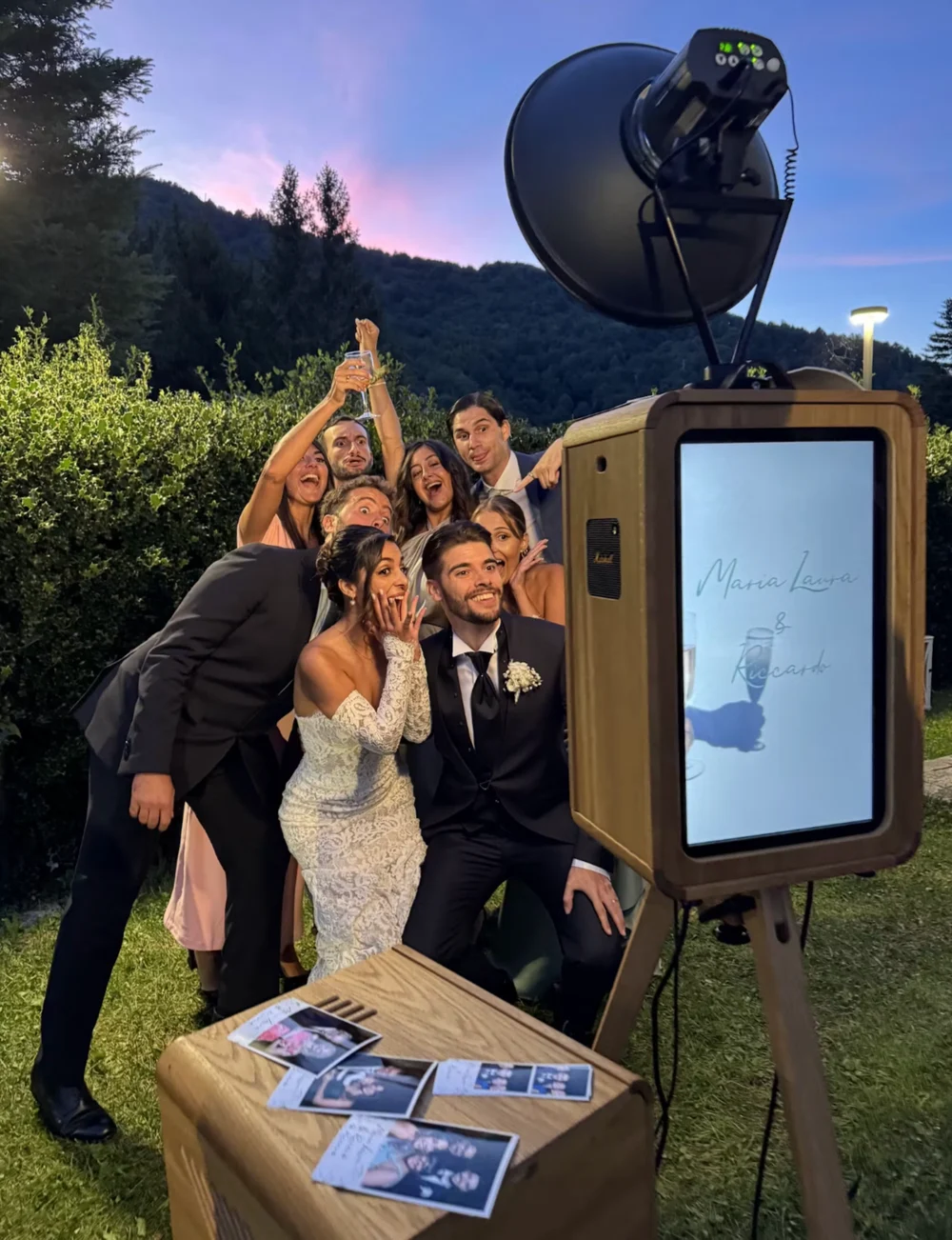 Sposi e invitati in posa davanti al photo booth all’aperto